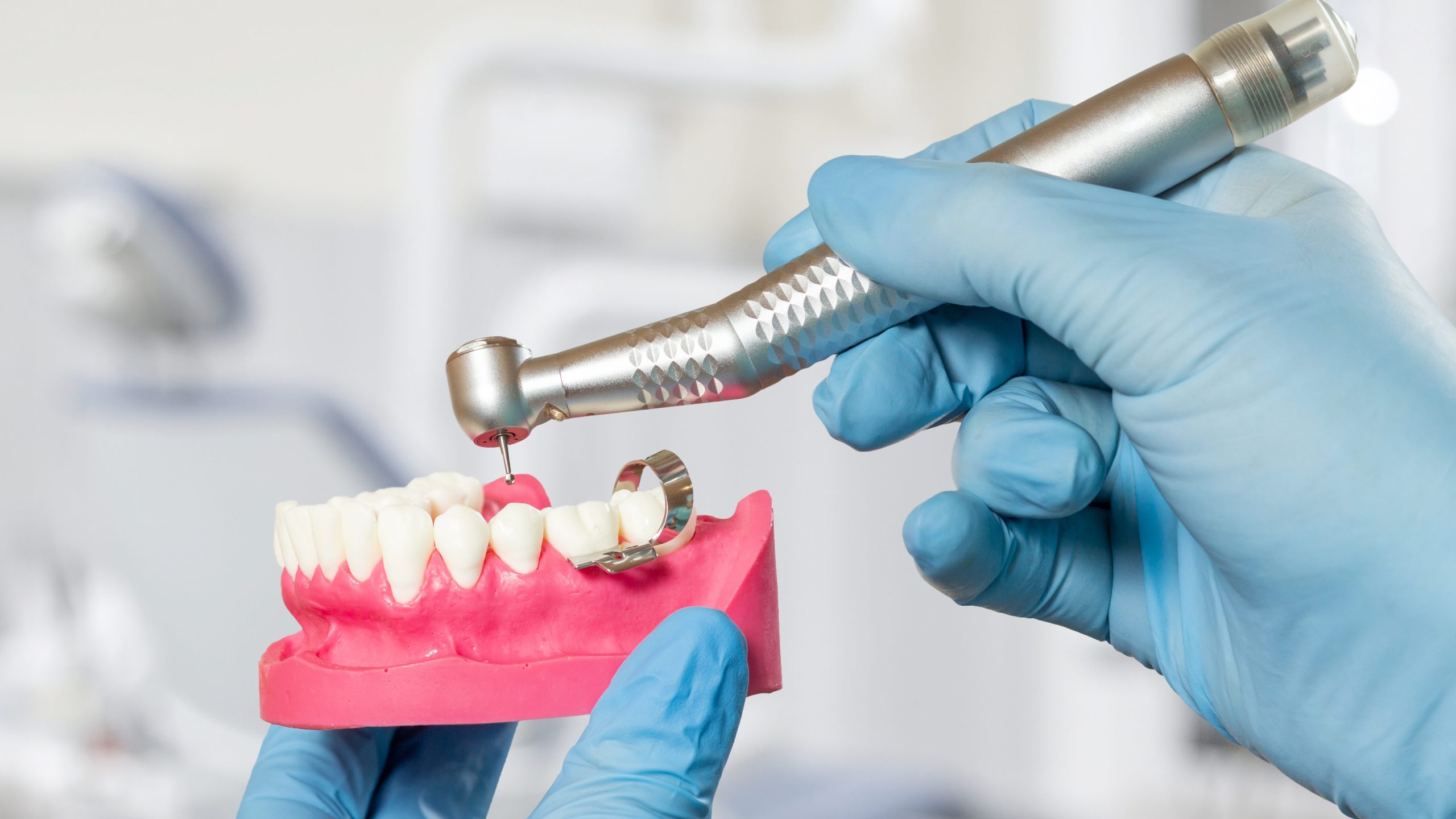 Head of high-speed dental handpiece with bur in dentist's hand.