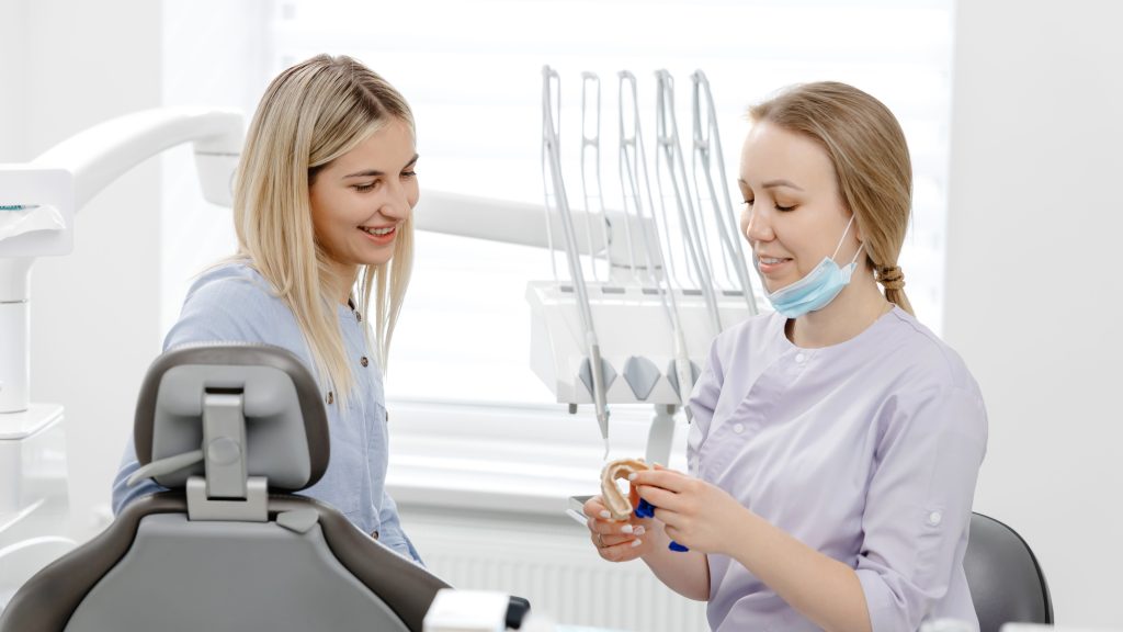 Dentist explaining treatment to patient using dental mold in clinic