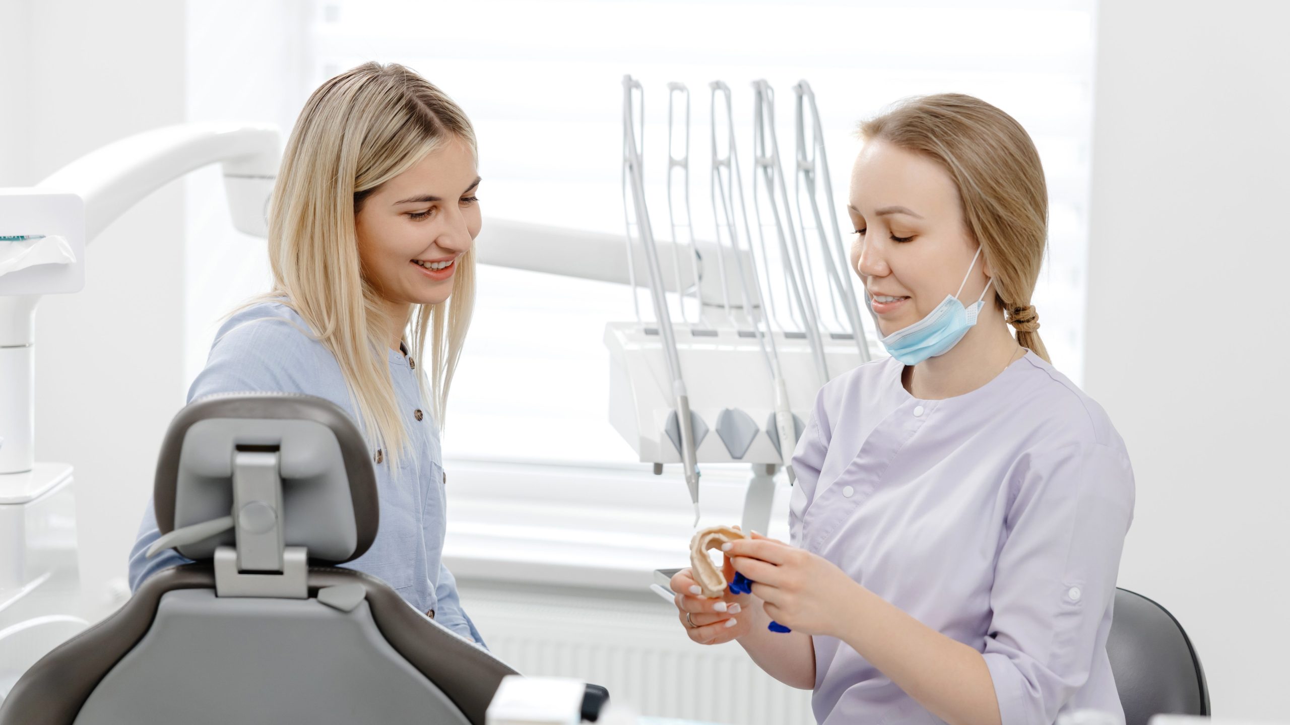 Dentist explaining treatment to patient using dental mold in clinic