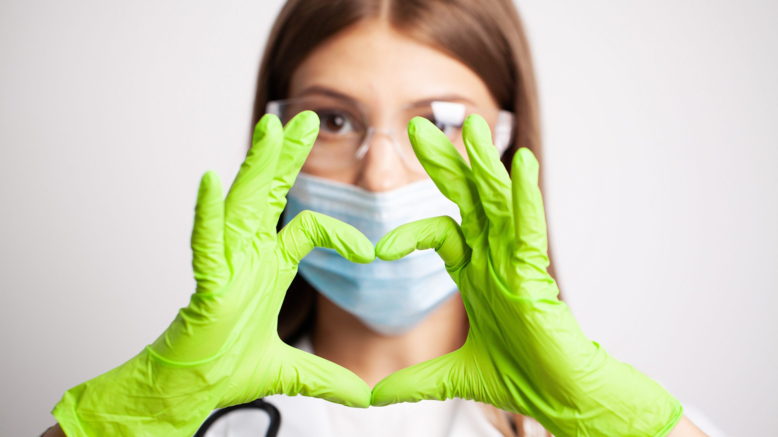 Female doctor in white coat shows hand a heart sign