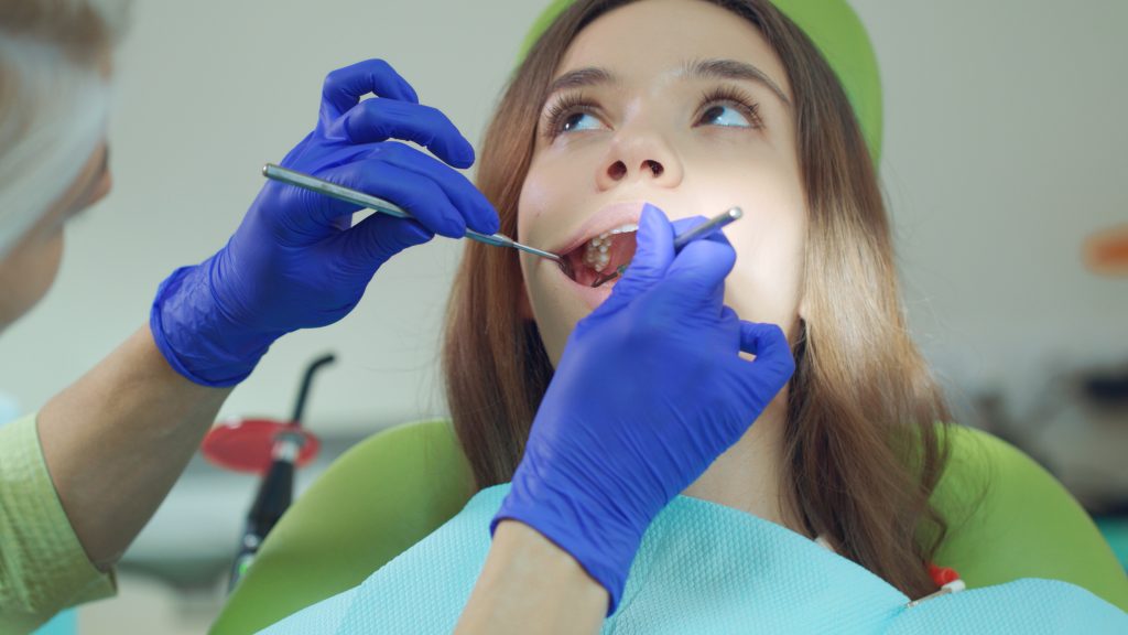 Female dentist examining patient teeth with dental tools. Medical treatment