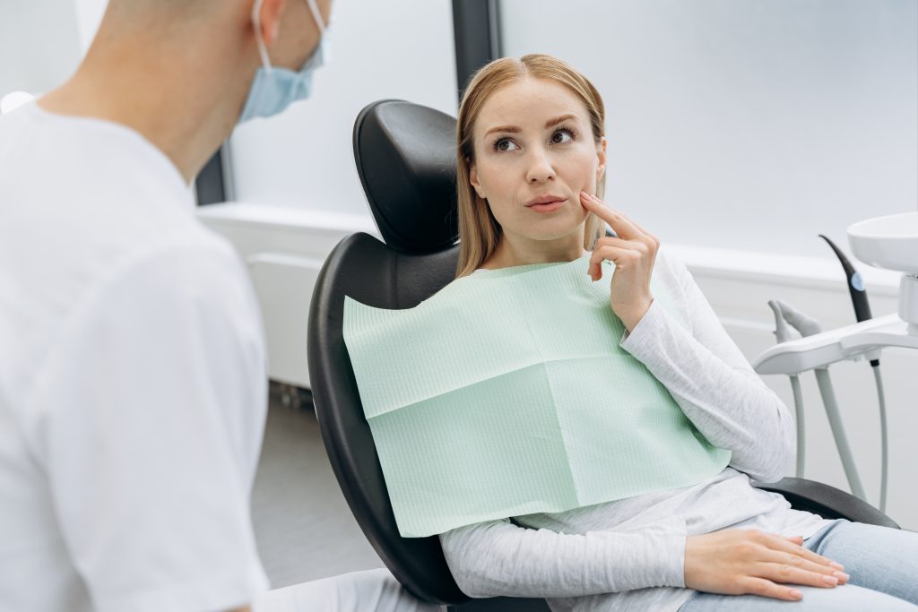 Beautiful, blond woman tells a dentist who has a toothache. Woman touches cheeks