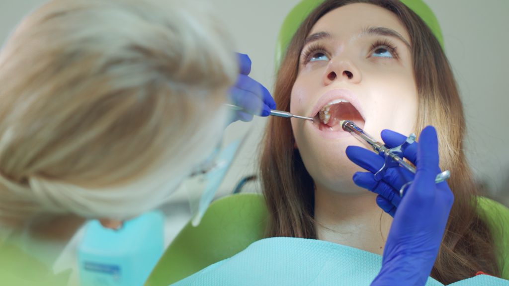 Dentist doing anesthetic injection in patient tooth. Patient in dentist chair