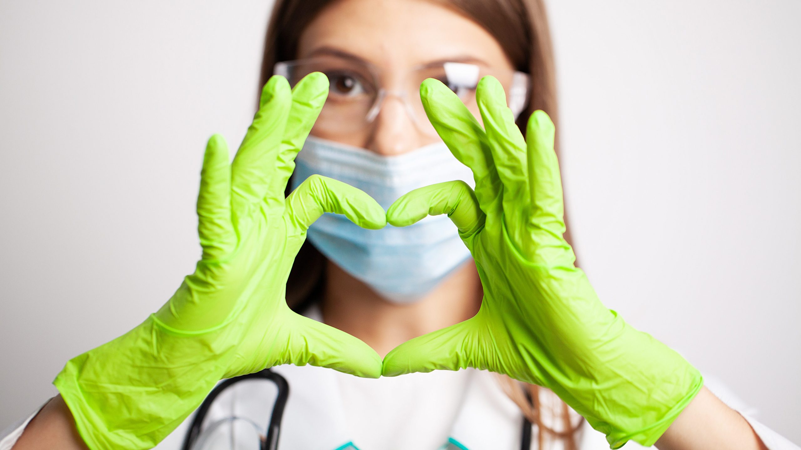 Female doctor in white coat shows hand a heart sign