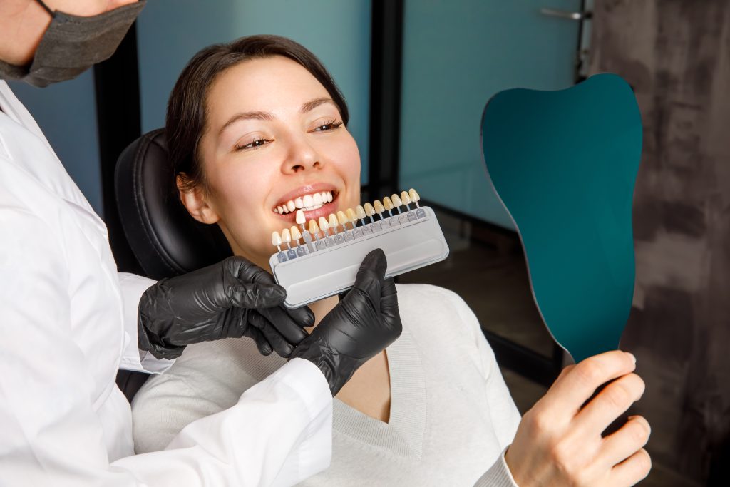 Smiling young woman. Cosmetological teeth whitening in a dental clinic. selection of the tone of the implant tooth